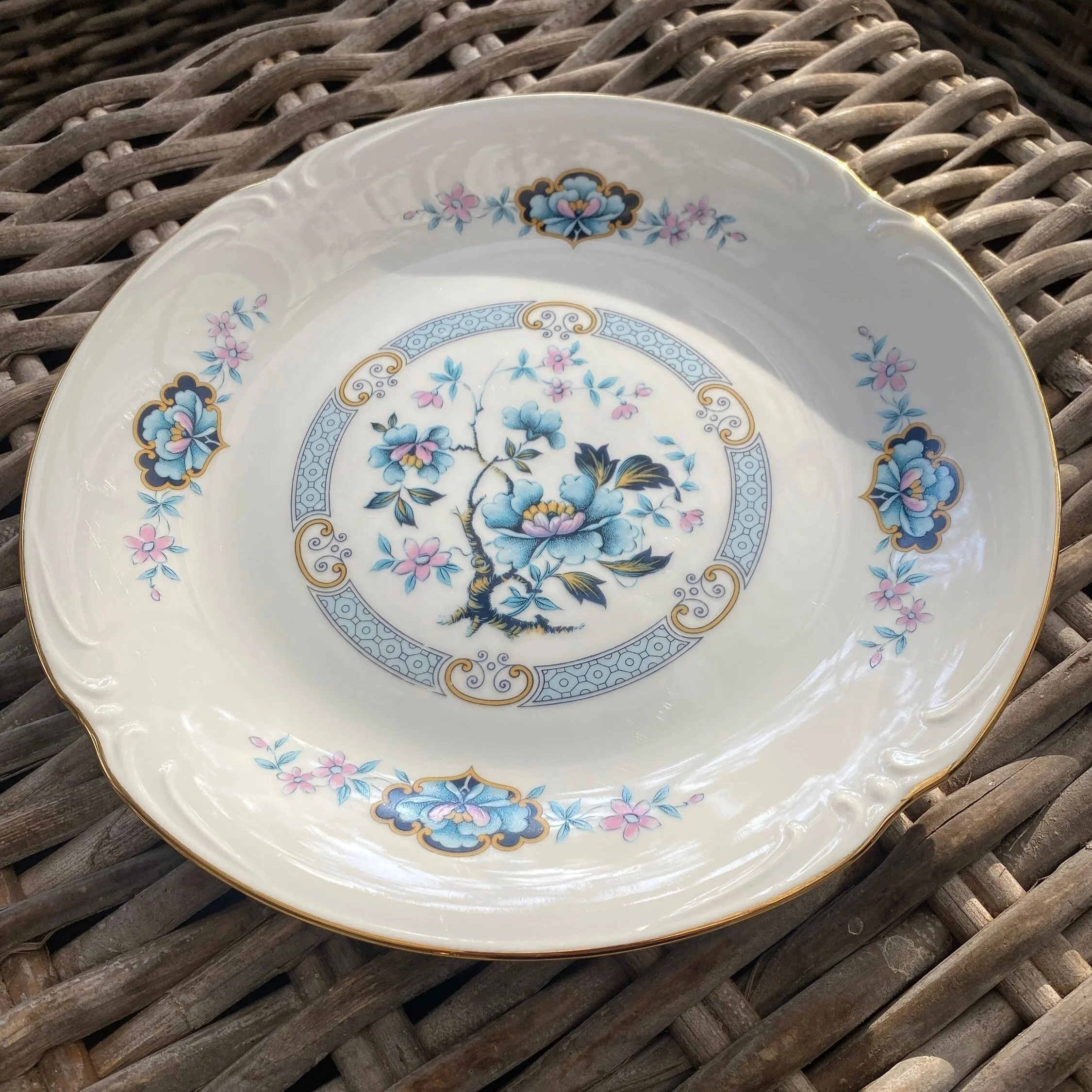 Angled view of the full plate resting on a woven surface, showing the overall decorative composition