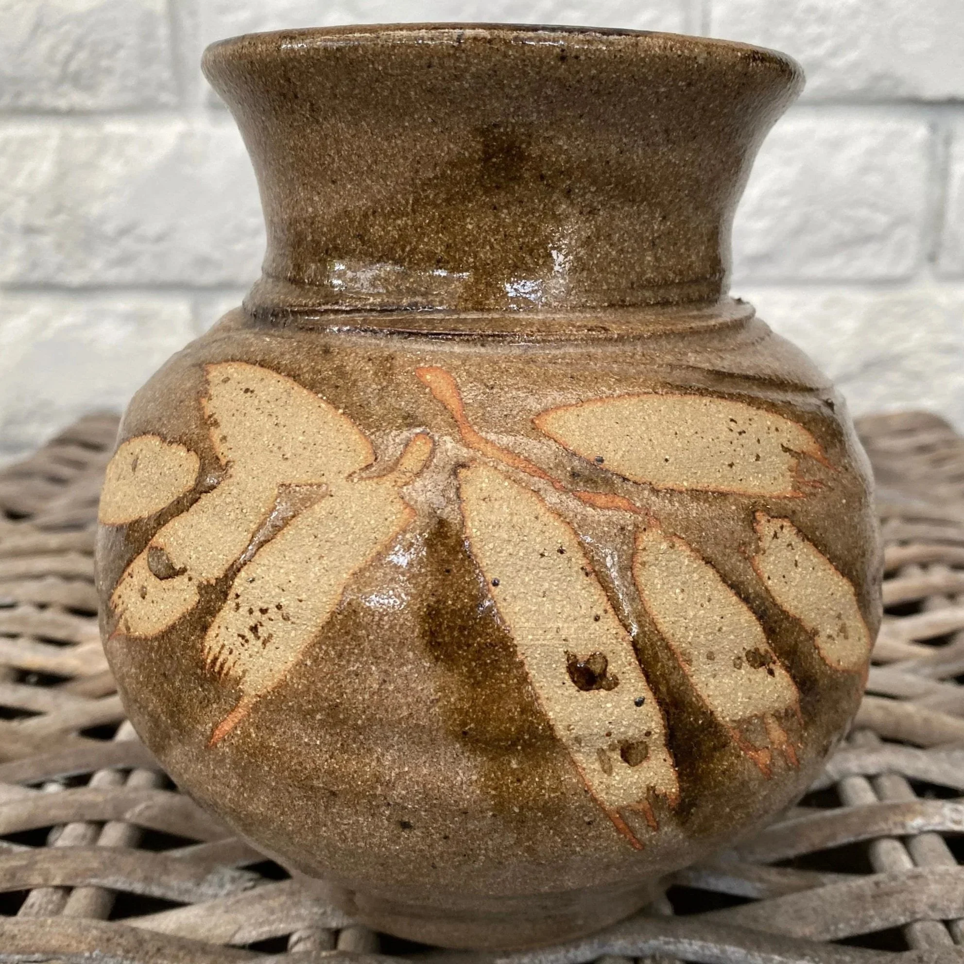 Front view of vintage pottery vase with ochre leaf motif on brown glaze