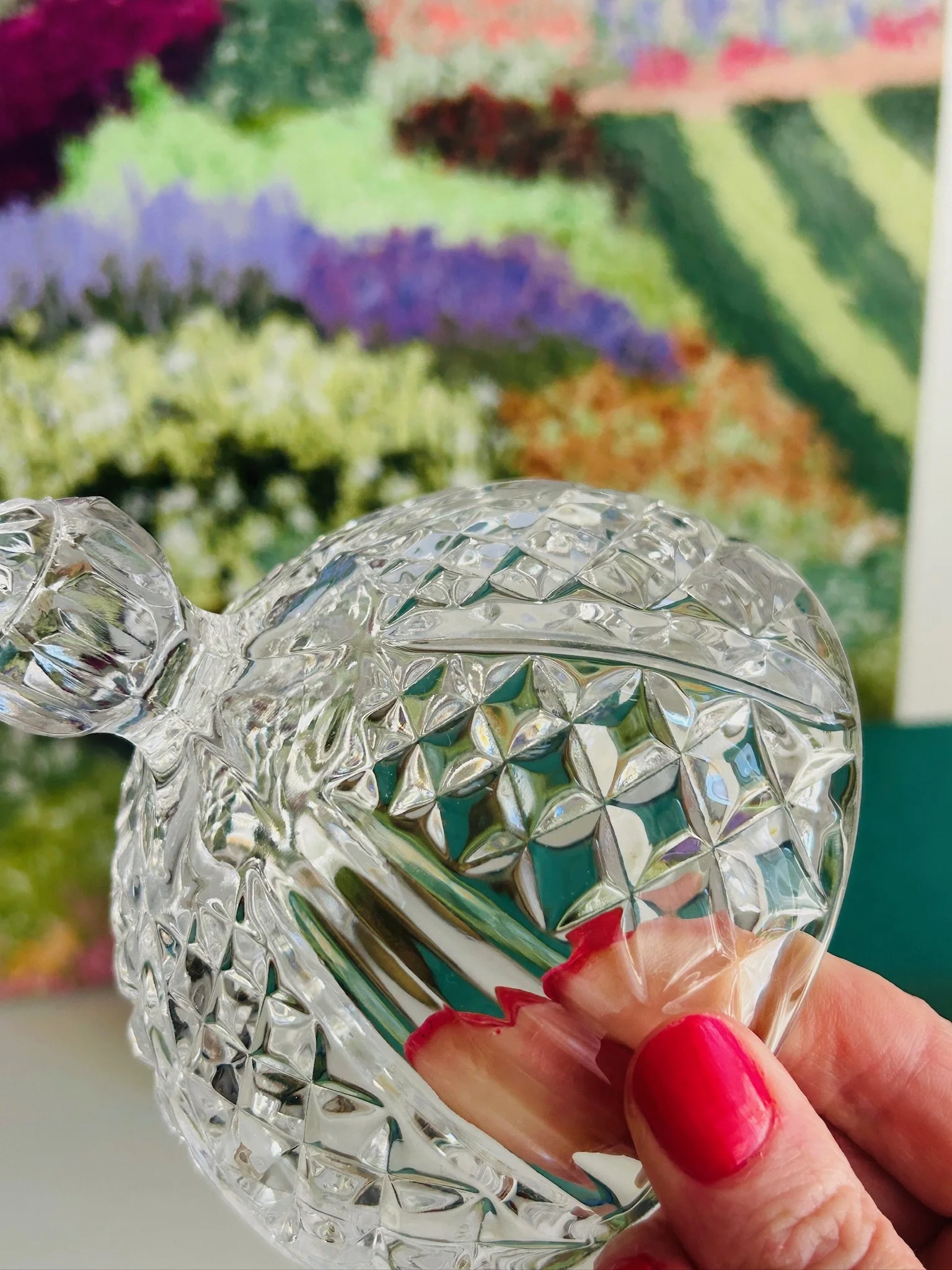 Top-side view of the crystal dish with the lid lifted open, showing the interior shape, cut pattern, and decorative hinge area.