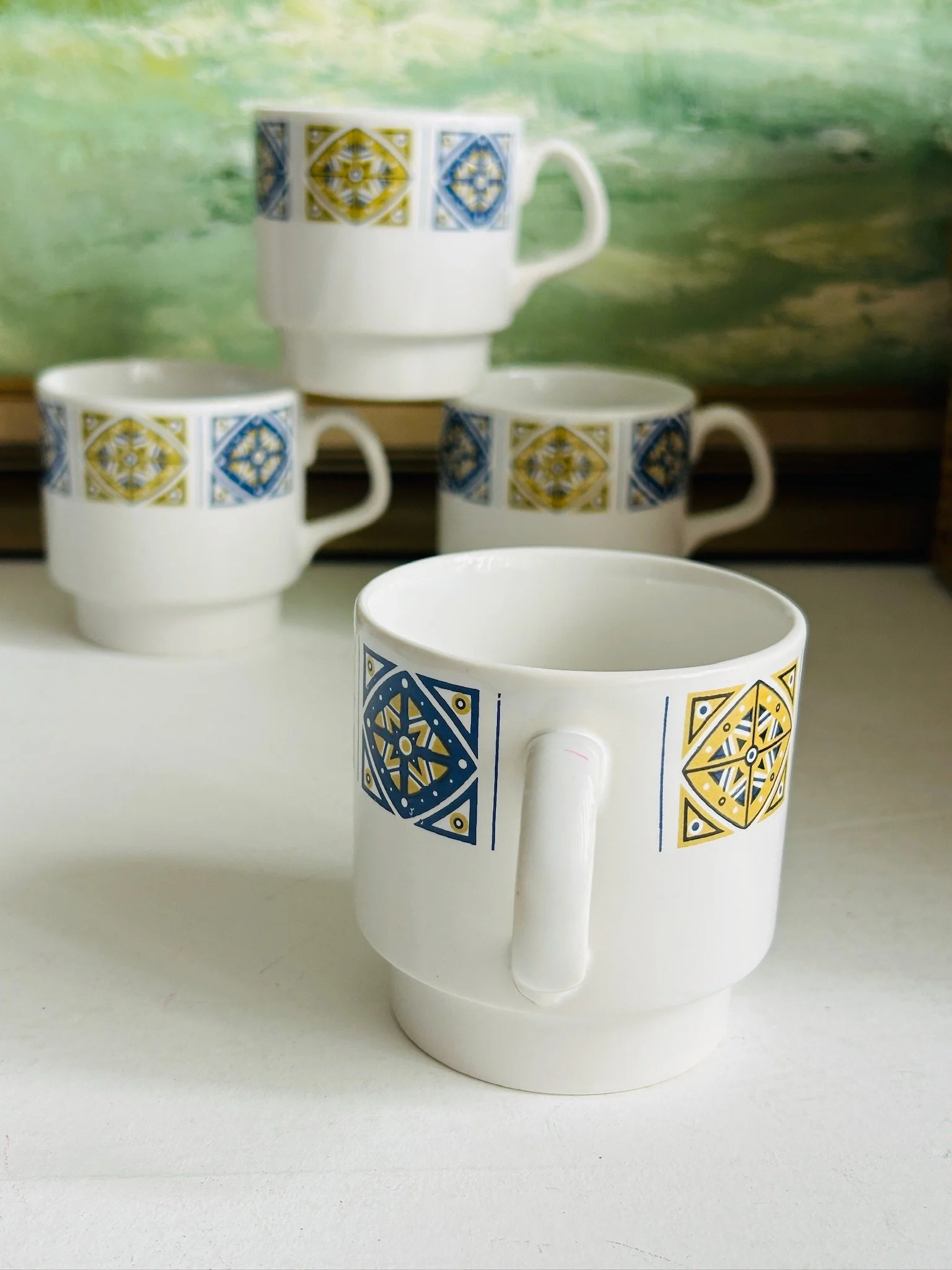 Staffordshire Midas ceramic coffee cup in the foreground with three matching cups behind, showing the retro geometric border pattern.