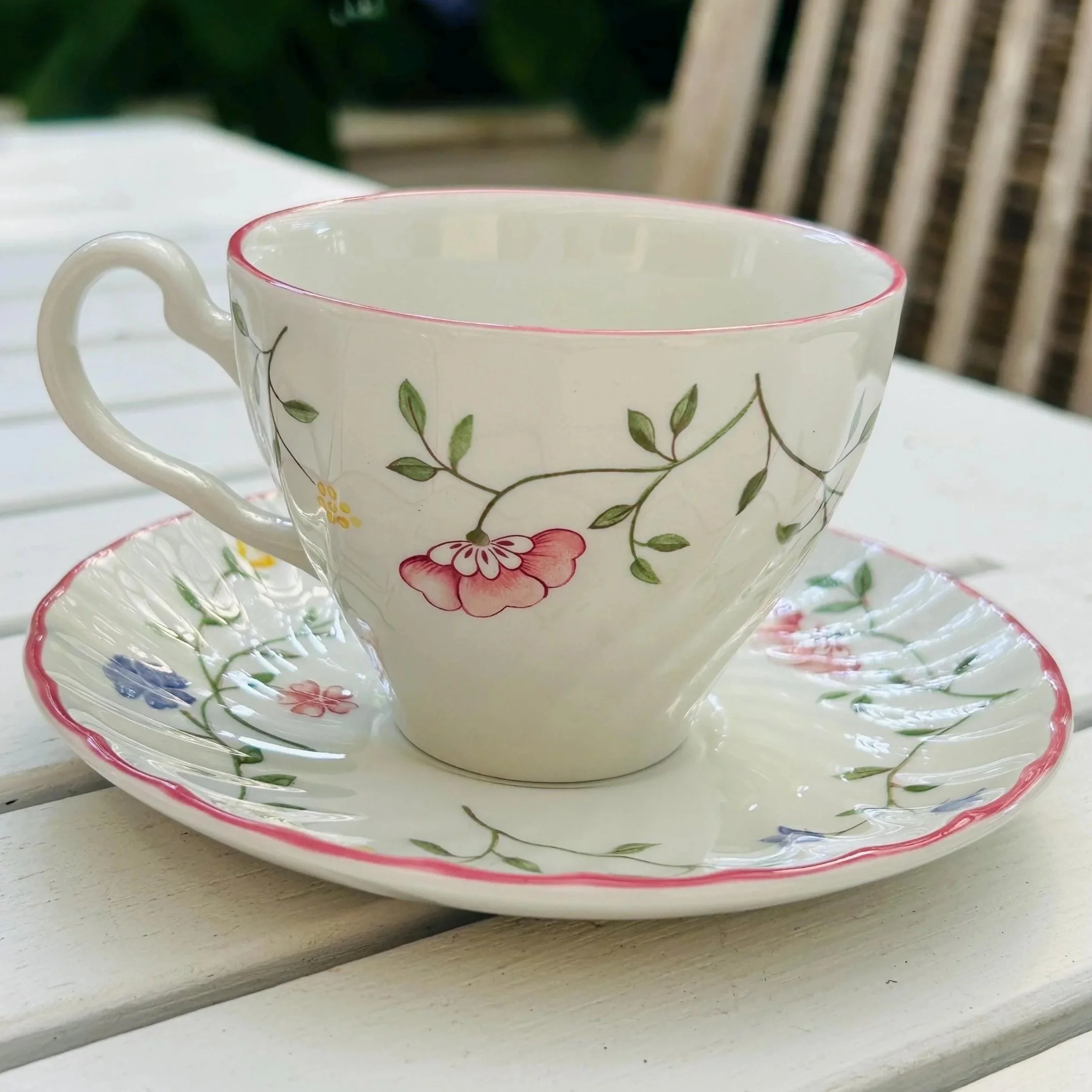 Teacup and saucer set on white table with visible floral design