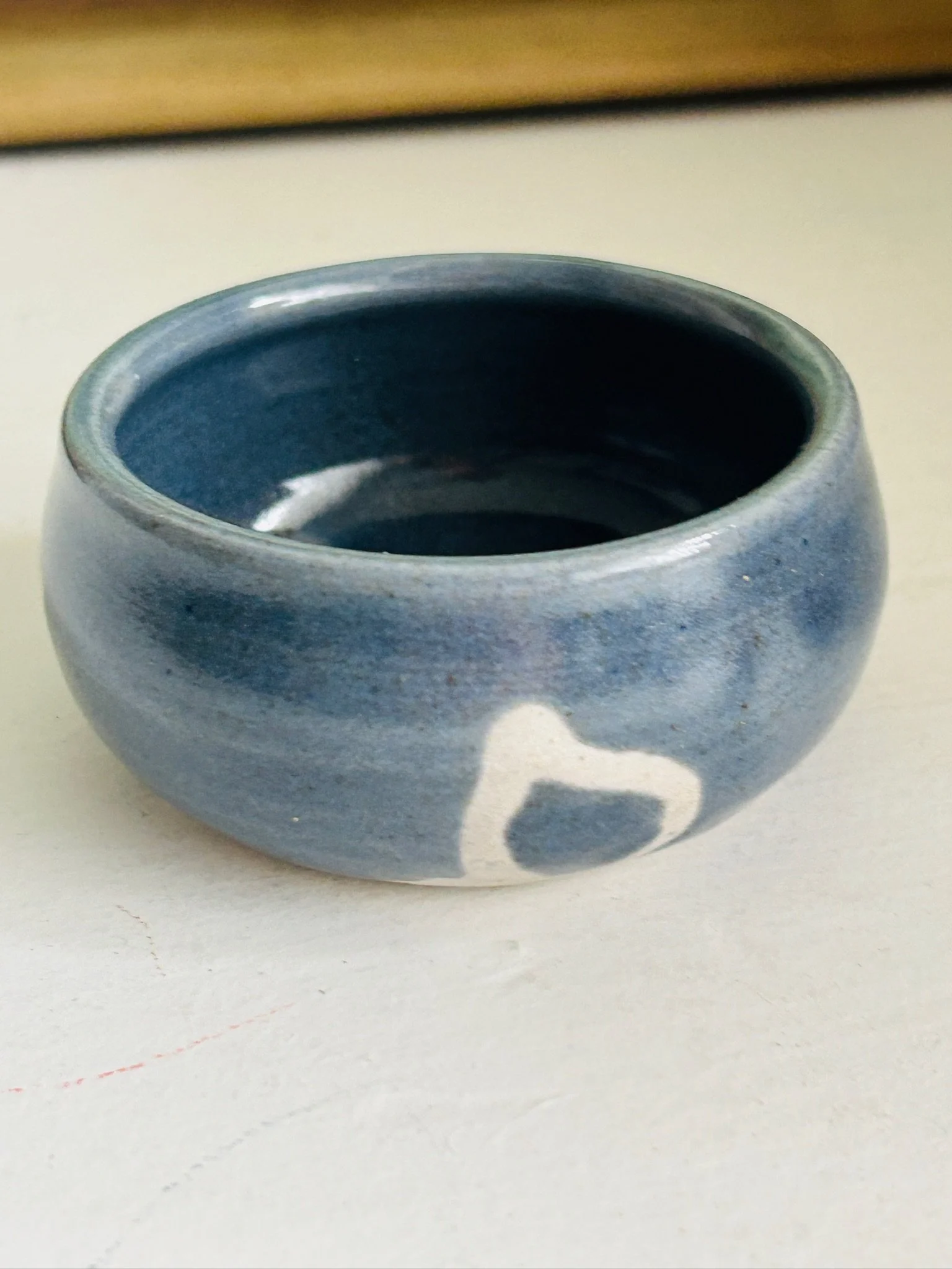 Angled front view of the signed pottery bowl highlighting the glossy glaze and organic clay ring design
