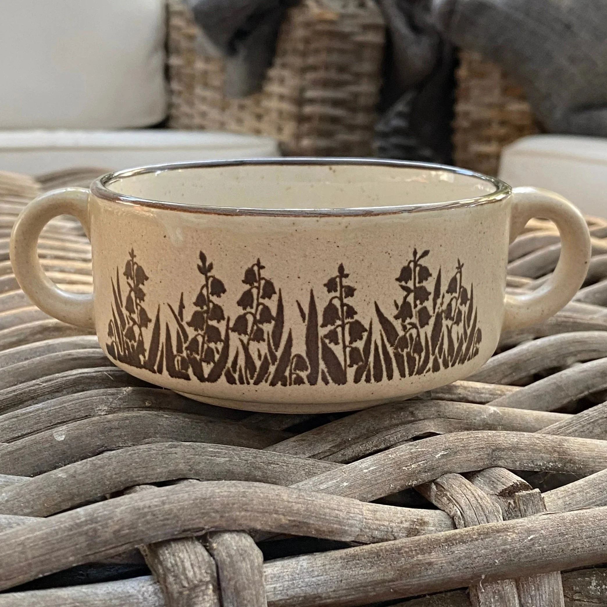 Front view of brown speckled stoneware mug with dual handles and floral motif