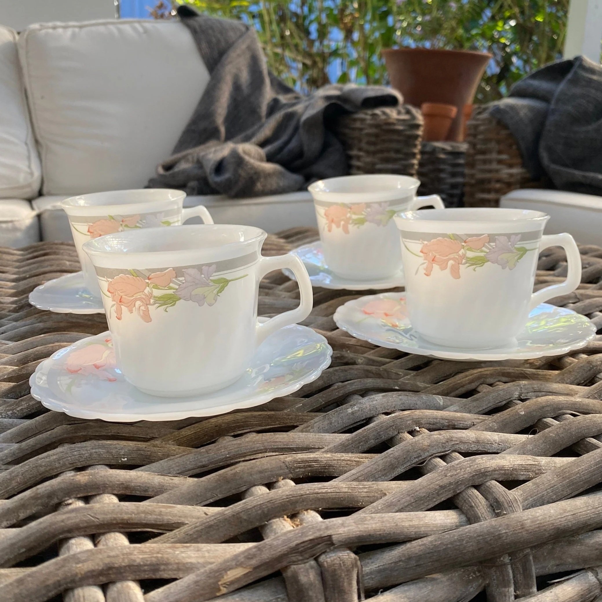 Full view of all four Indopal cups with matching saucers on wicker surface