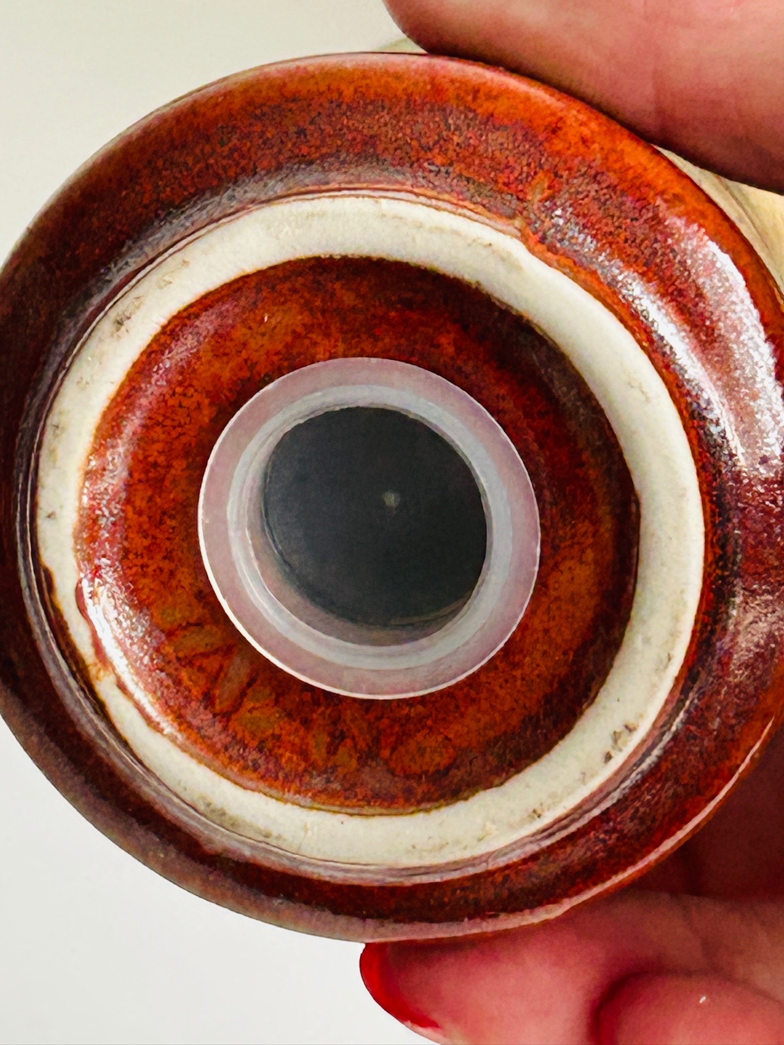 Underside base detail of one shaker showing the circular stopper opening and concentric glazed rings.