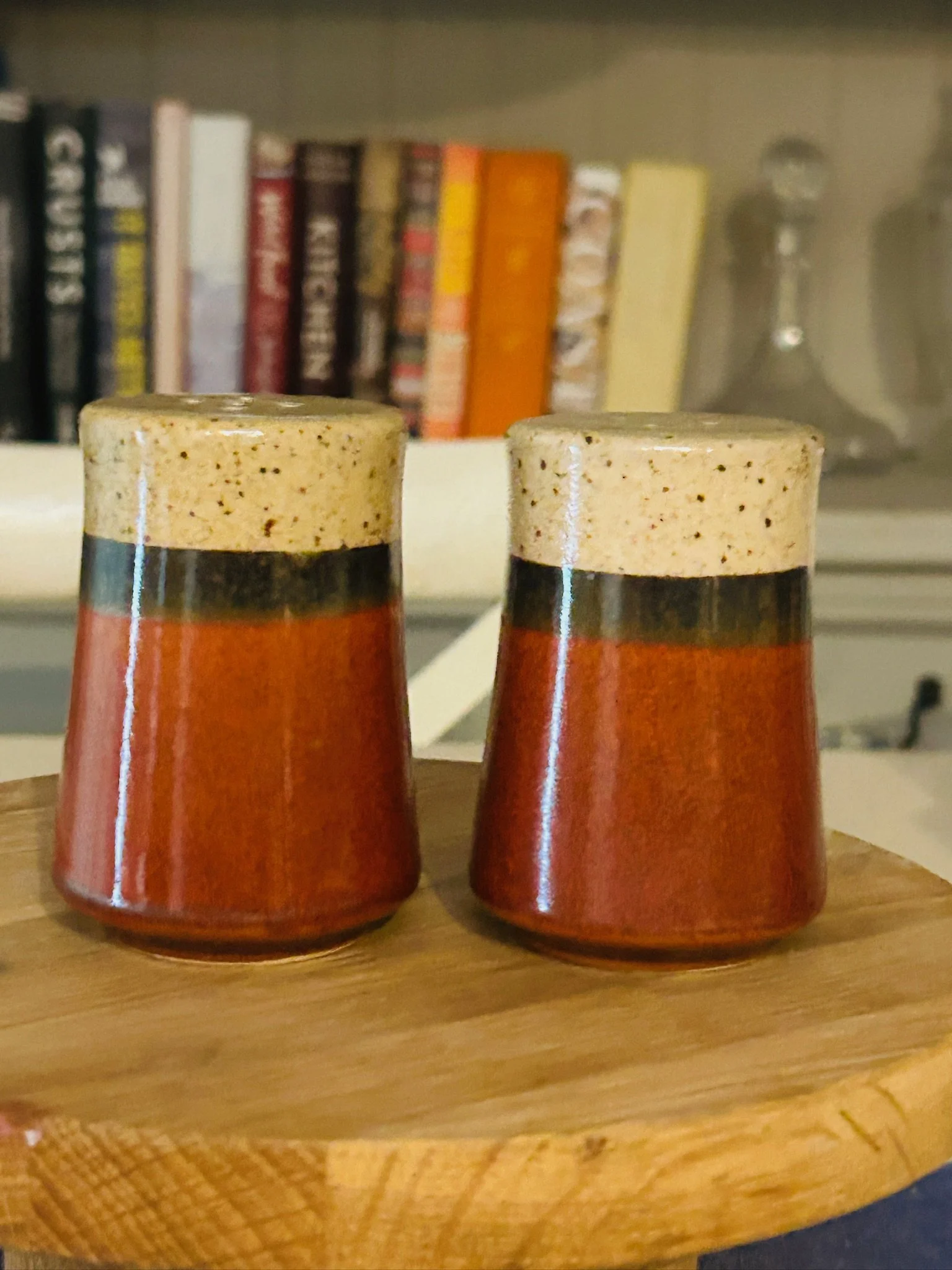 Pair of Japanese tri-tone ceramic salt and pepper shakers displayed together on a wooden surface with books in the background.