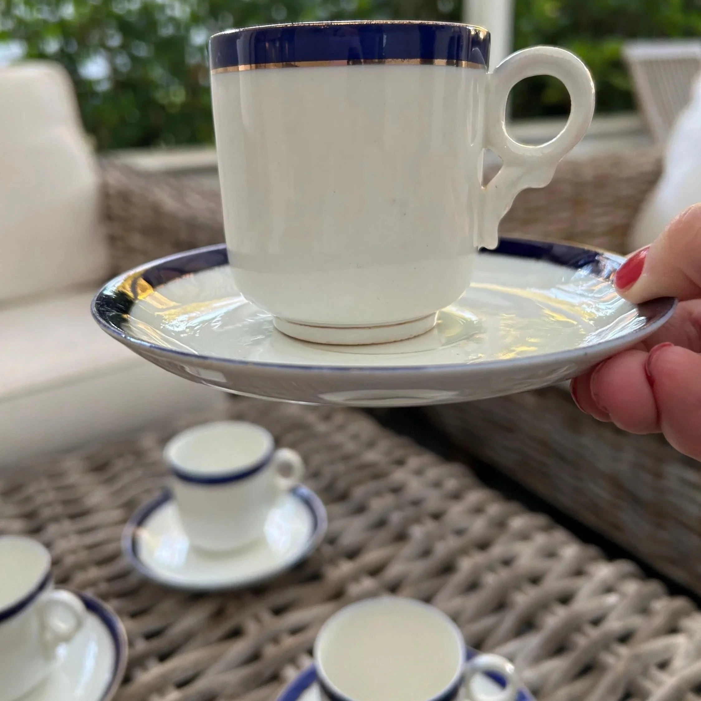 Side view of cup and saucer duo held by hand showing delicate handle and clean glaze