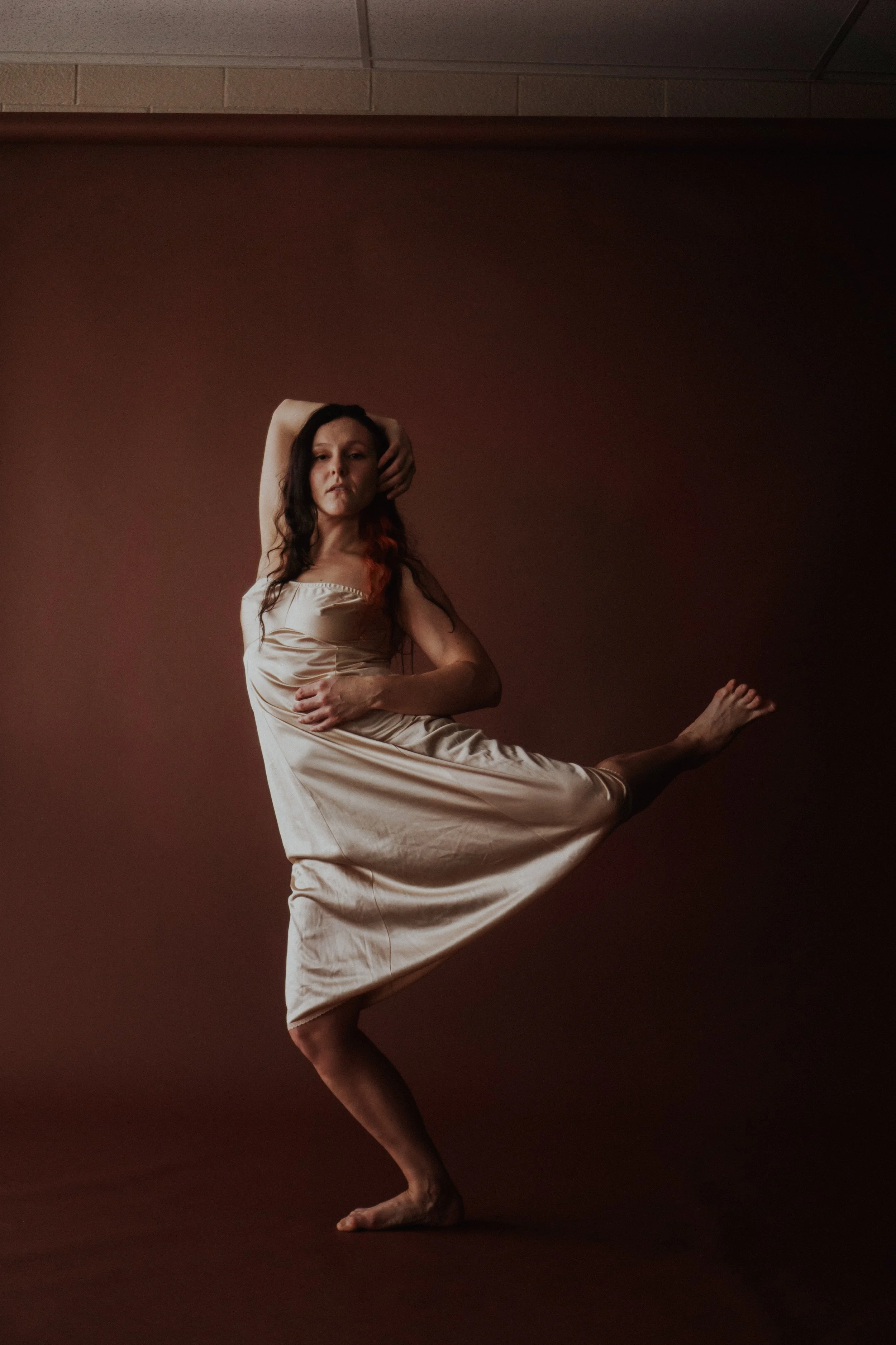 A woman in patterned pajamas dancing or performing in front of a plain peach background.