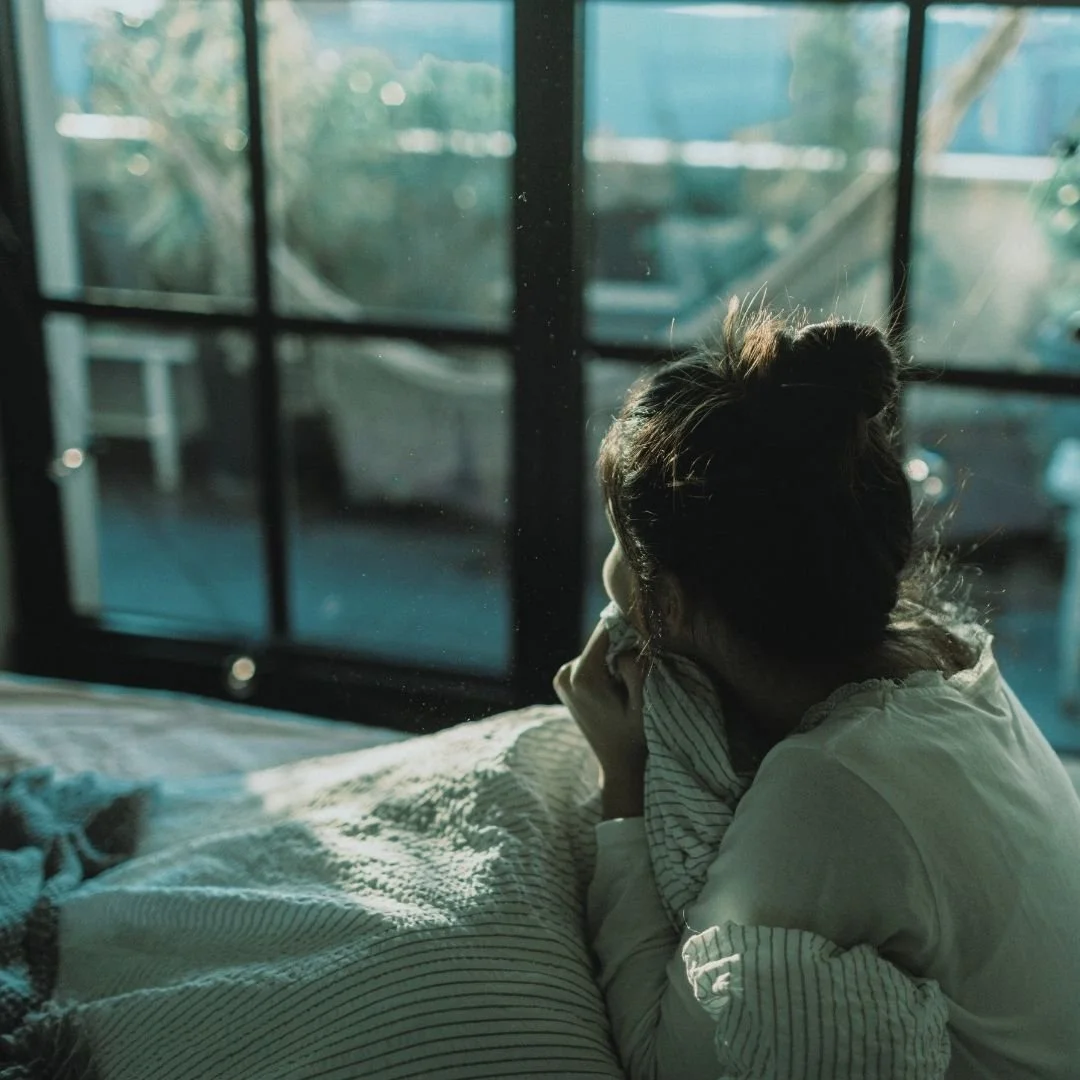 Eine Frau die wegen Angst und Unruhe in der Nacht wach im Bett sitzt.