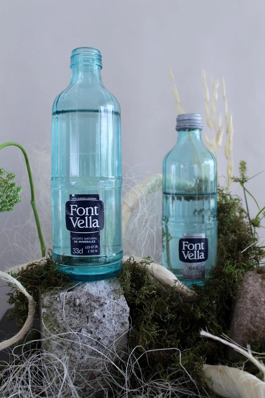 Font Vella bottles integrated into a contemporary floral installation with natural materials.