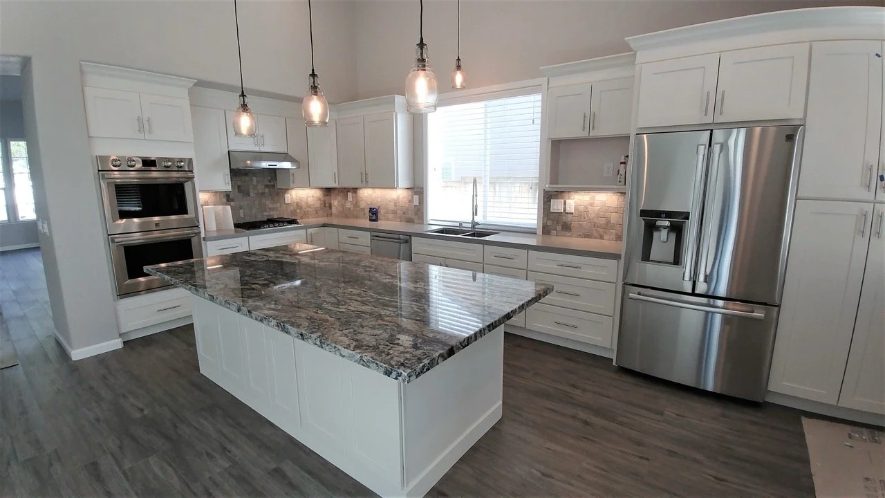 Remodeledkitchen_graymarblecounters_modernlightfixtures_stainlesssteelefridge.jpeg