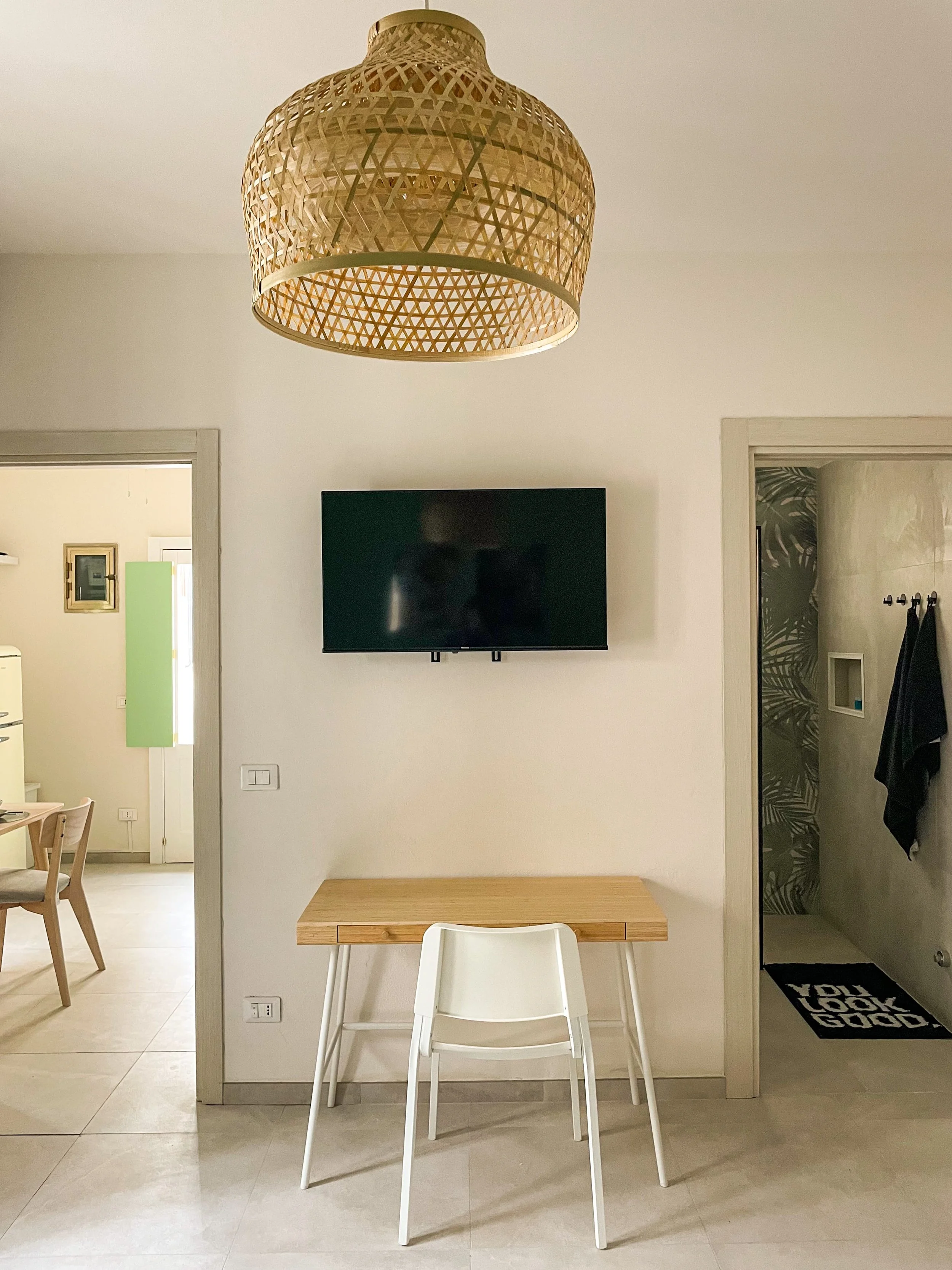 View inf front of the bed with desk and smart tv. 