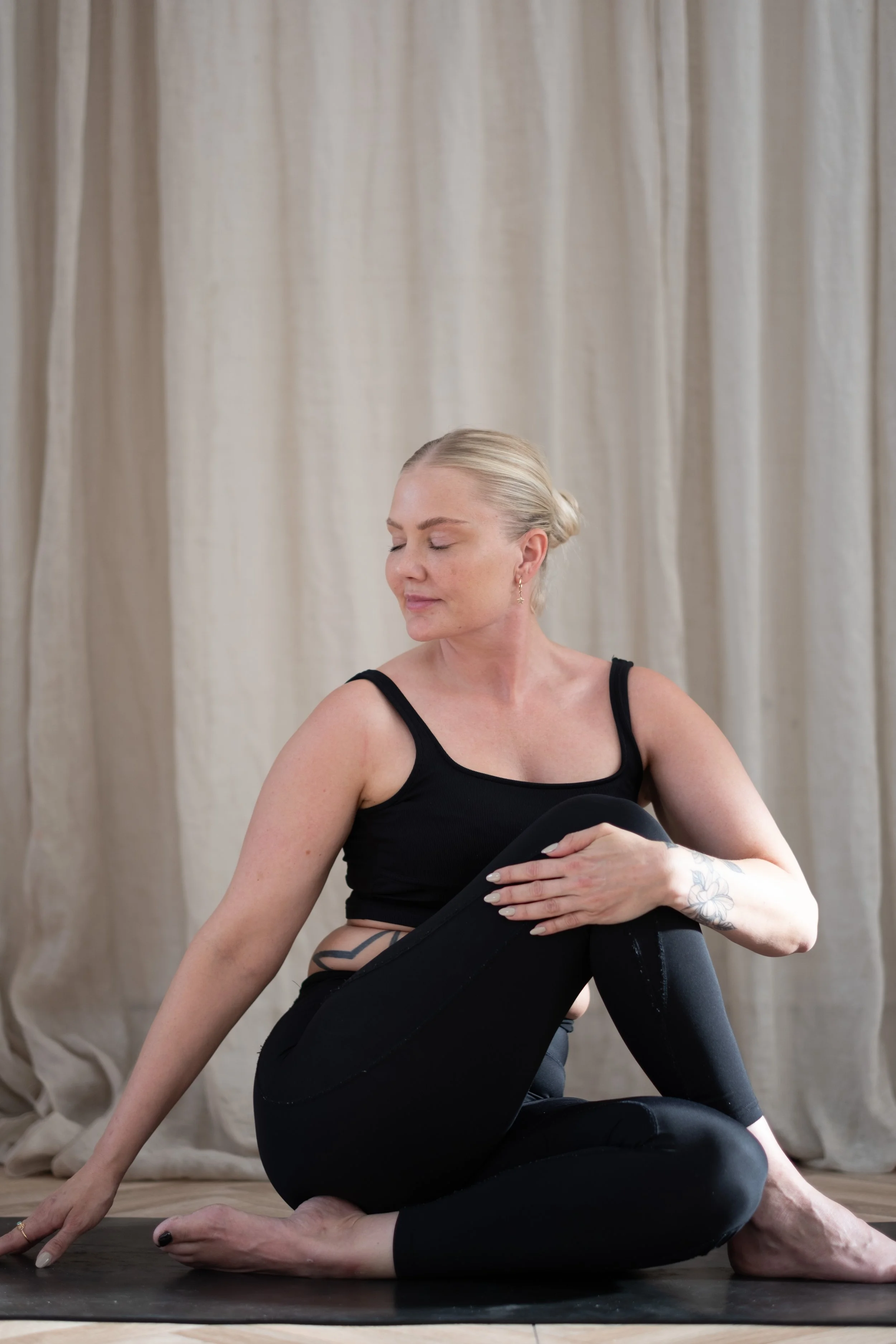 A woman with dark curly hair resting her head on a black cushion on the floor.