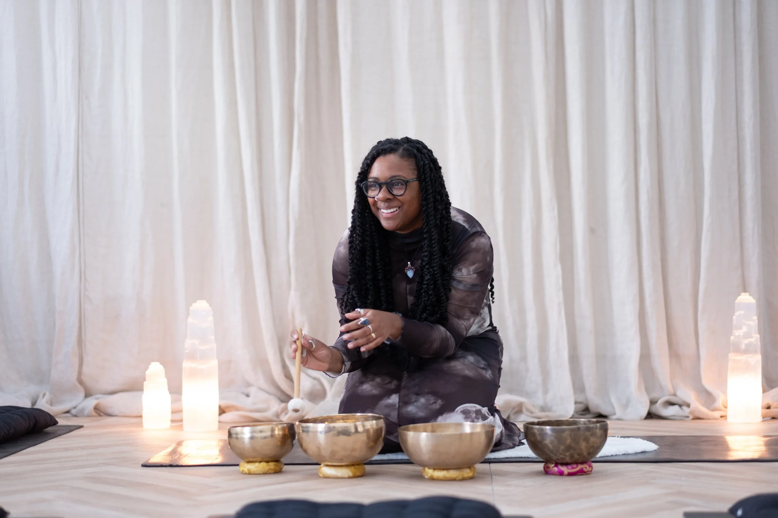 A woman with dark curly hair resting her head on a black cushion on the floor.