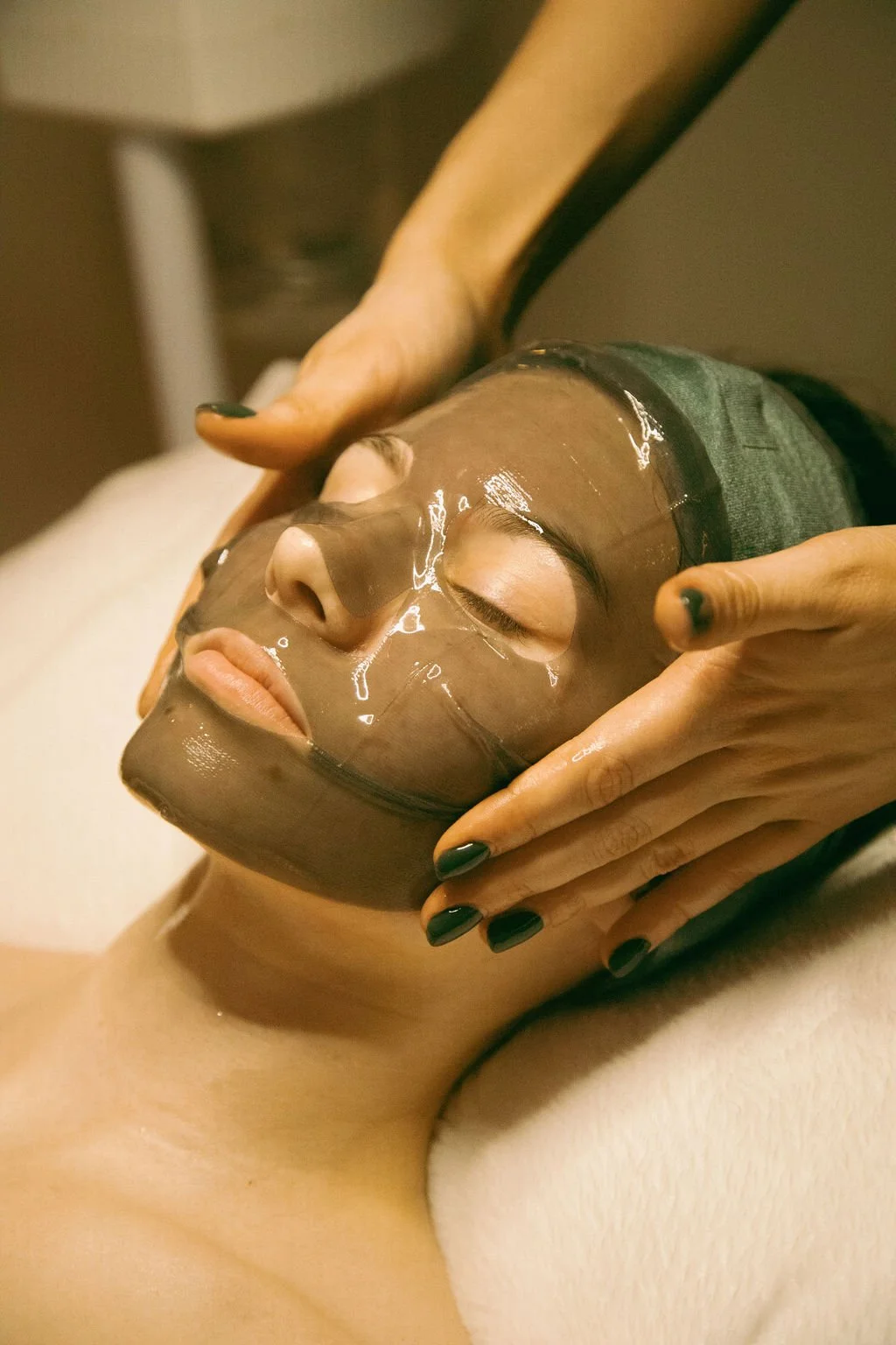 Person receiving a facial treatment with a clay mask at a spa
