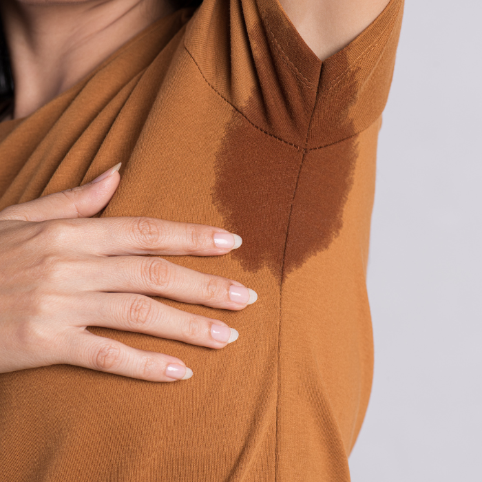 image of a person with their arm up and sweat marks on their shirt.