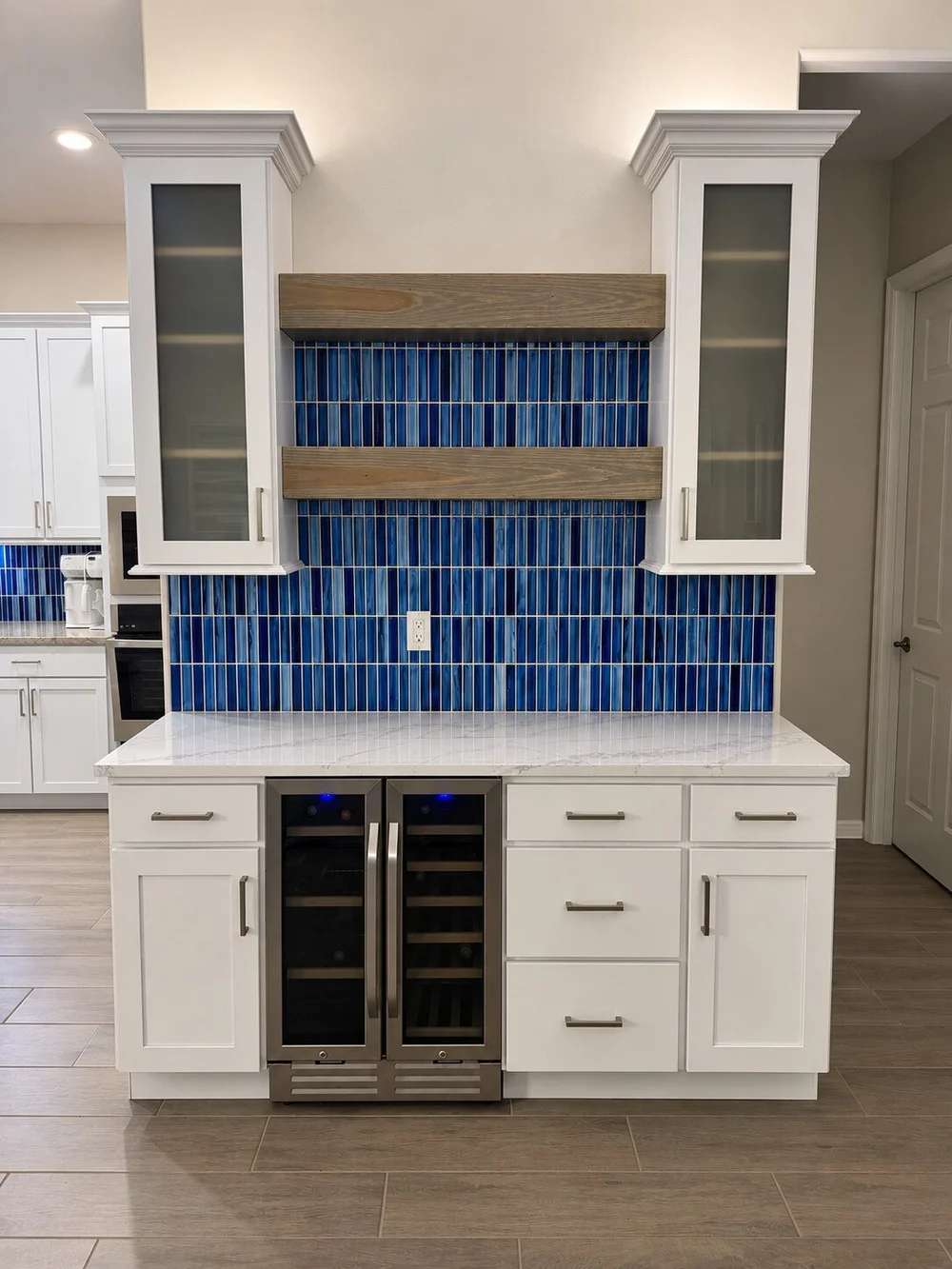 Finished home bar with blue tile, floating shelves and glass-front cabinets