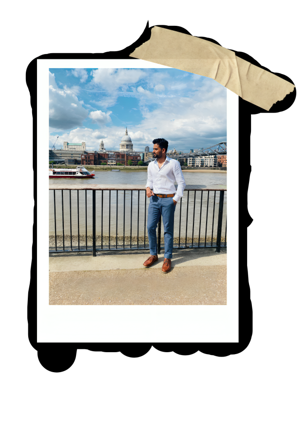 A man in a white shirt and blue pants standing by a railing by the river, with London landmarks including St. Paul's Cathedral and the Millennium Bridge in the background.