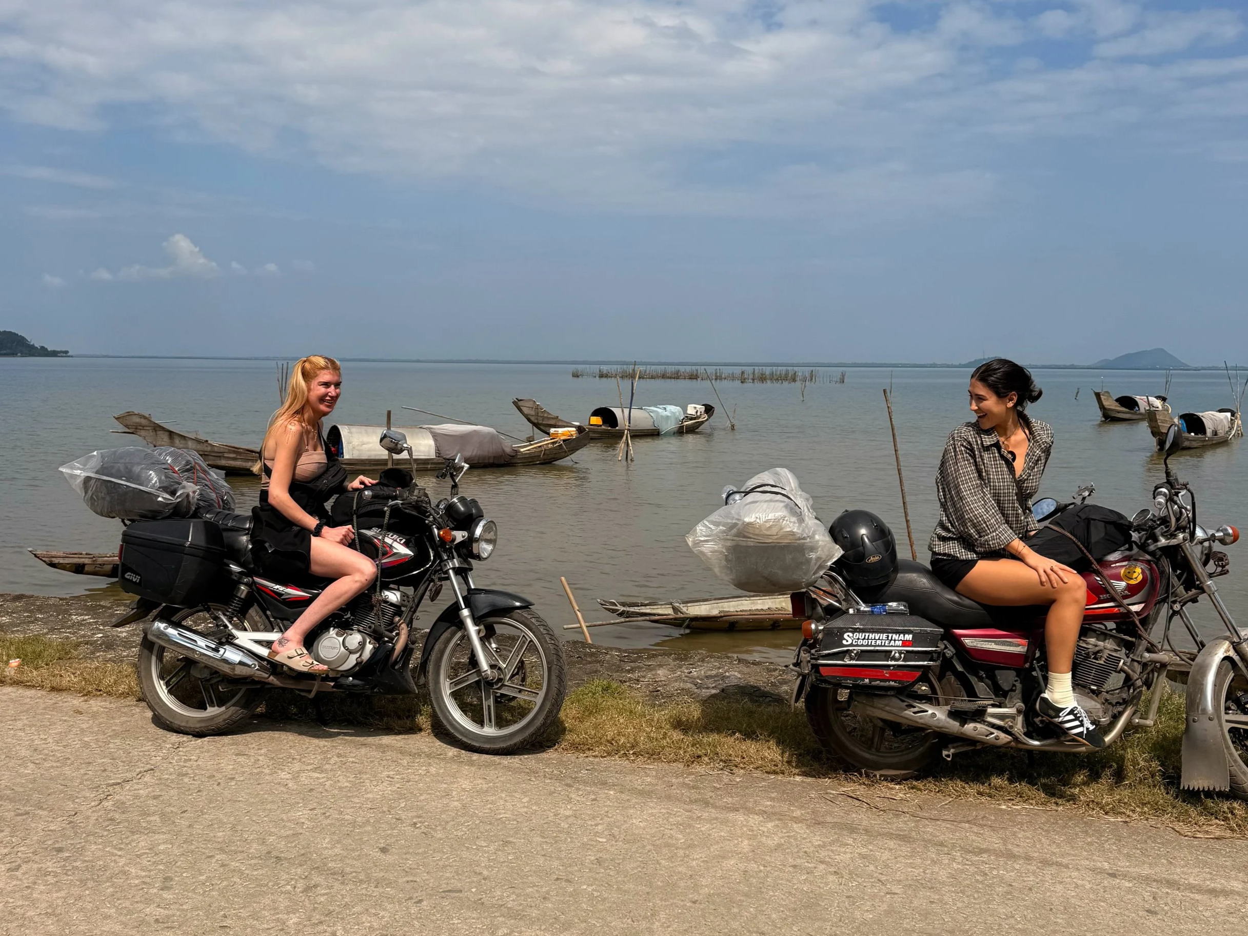 two women riding motorbikes vietnam lake fishermen boats