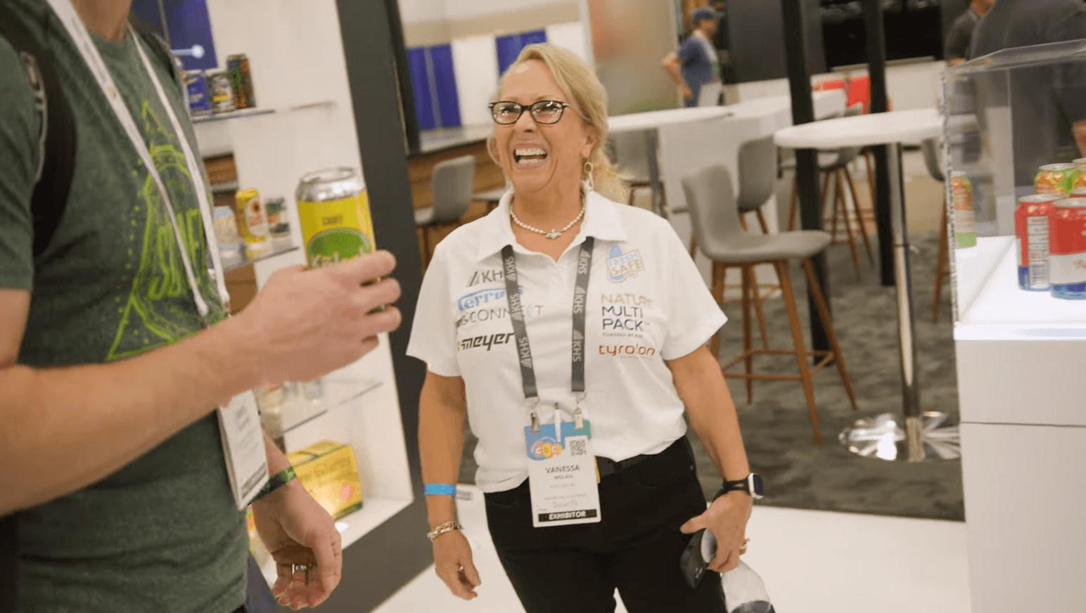 Trade show exhibitor engaging with attendee at a busy conference