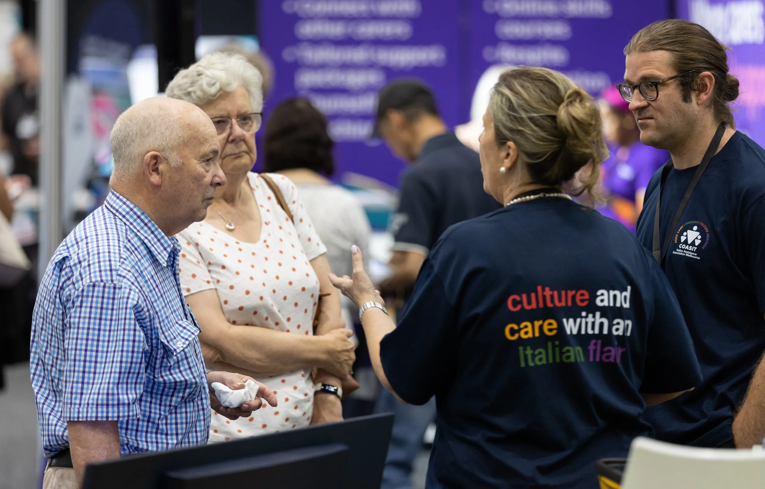 Person serving cookies at a trade show booth with Regents Garden retirement villages signage.