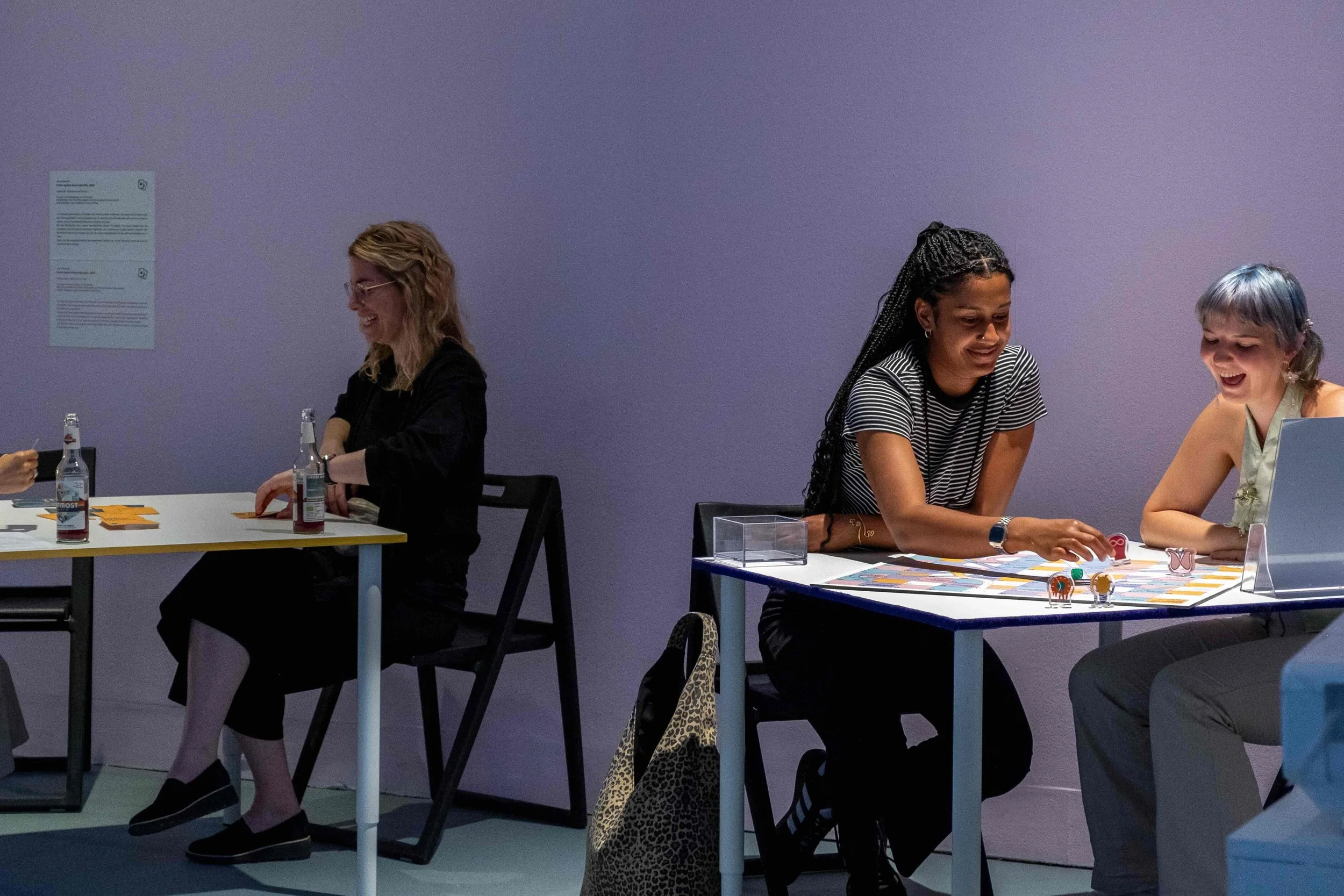 A couple plays the board game, while another one plays a card game on a different table. Photo: Mareike J. Lange. Event: “In Conversation” exhibition, 2025.