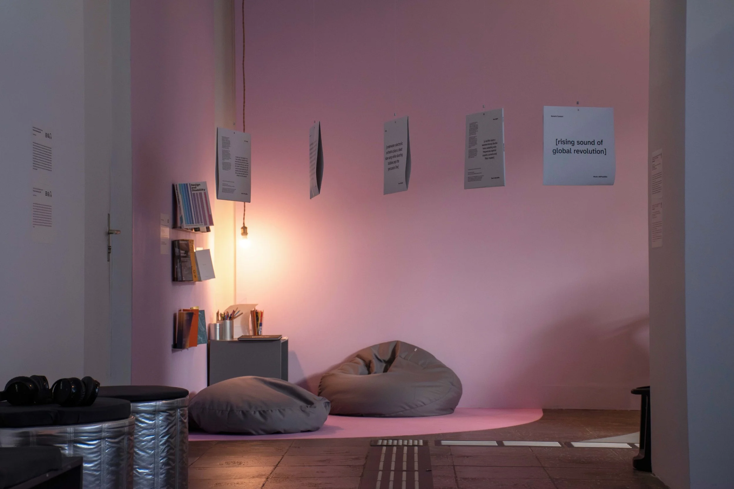 Another series of five hung vinyl covers, with a reading corner and one hung light as a background. Photo: Dani Hasrouni. Event: “In Conversation” exhibition, 2025.