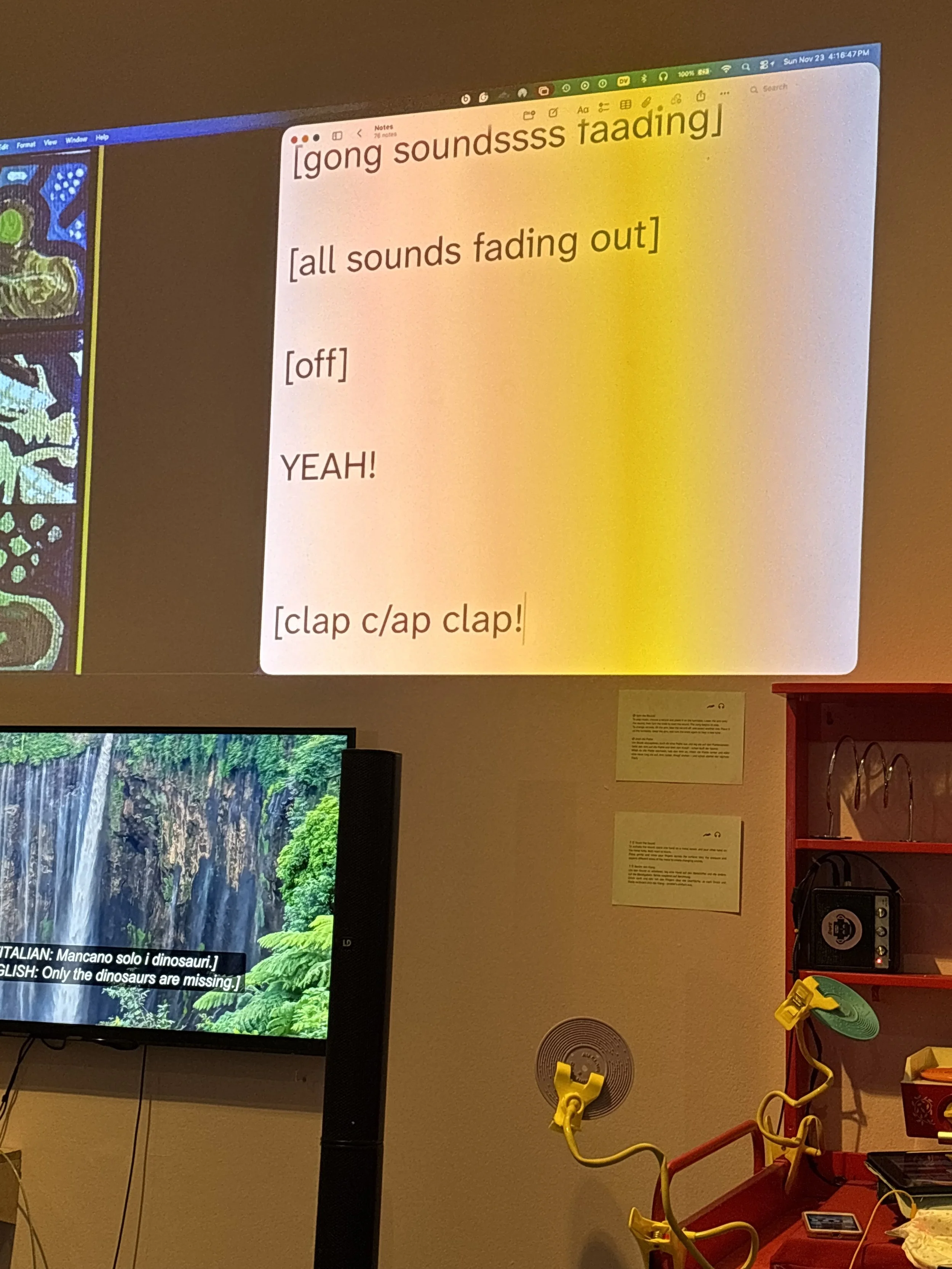 Sound captions projected on a wall. They interpreted the overall soundscape. They read, “[gong soundssss faading] [all sounds fading out] [off] YEAH! [clap c/ap clap!” Photo: Terry Perdanawati. Event: “In Conversation” exhibition, 2025.