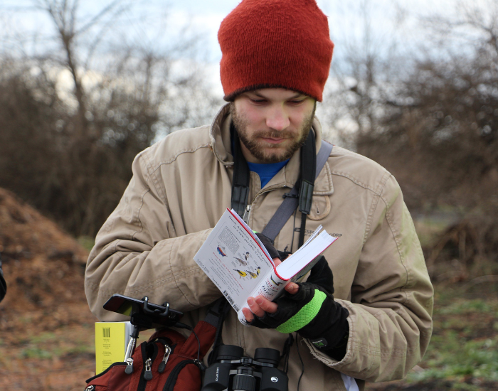 Getty Images a person looking at a bird guide and many adventure gear