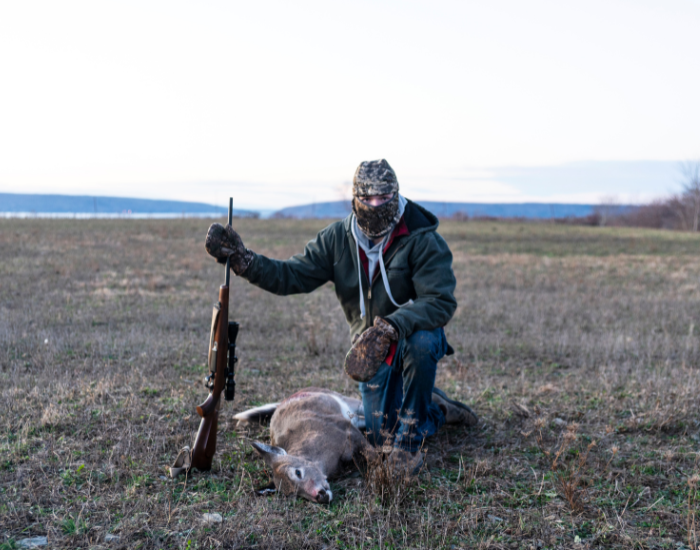 Getty Images a young hunter next to a dead deer on a grassfield