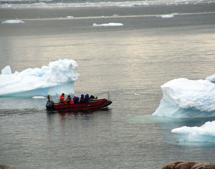 a tourist boat navigating in antarctic water surround by ice caps