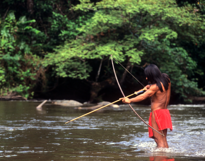 indigenous hunter with a bow on a river