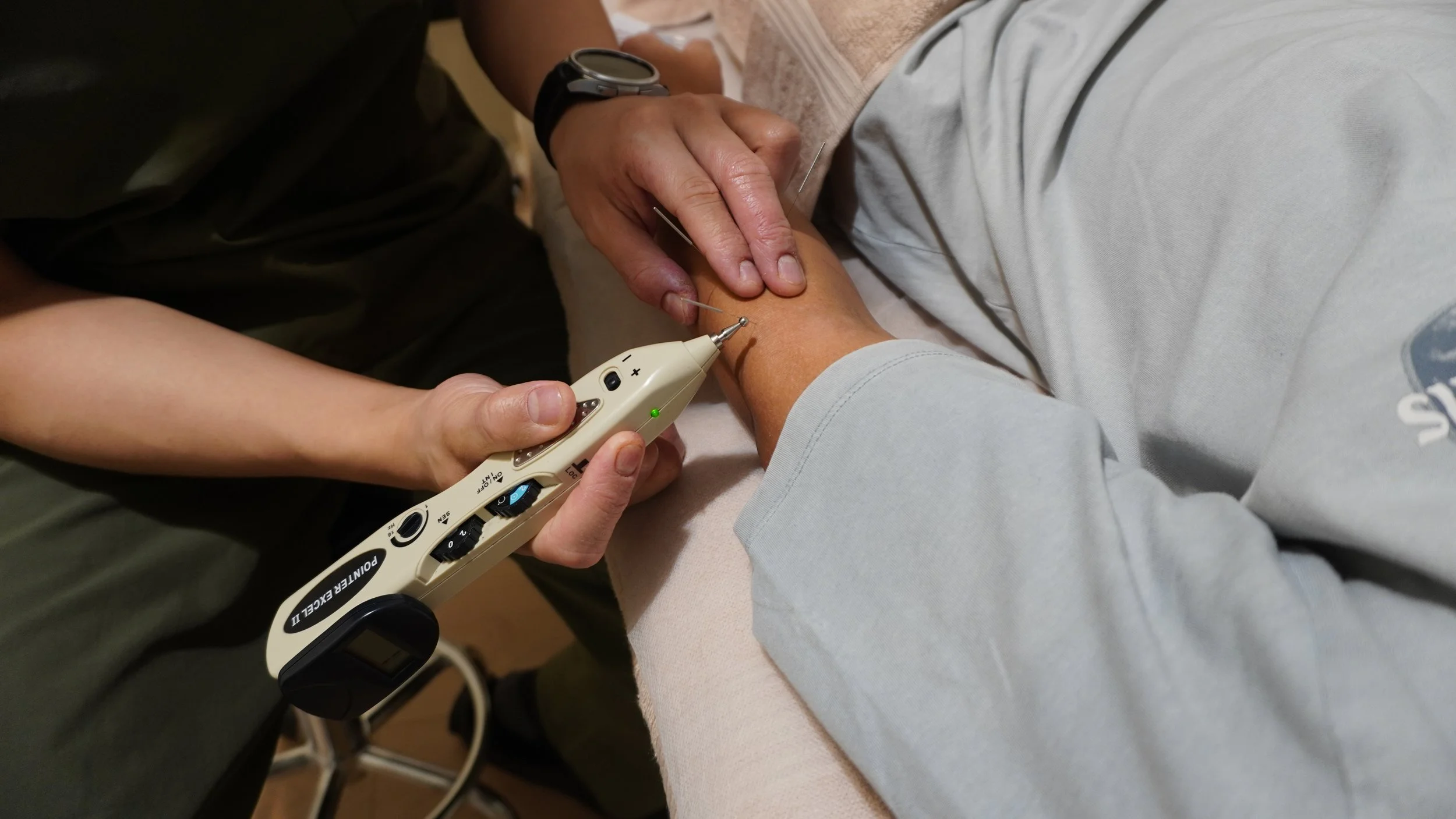 A healthcare professional using a point-of-care device to perform a blood test on a patient's forearm.