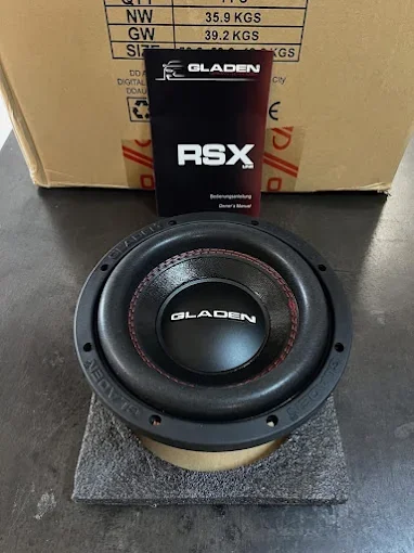 Un haut-parleur audio de la marque Gladen RSX placé sur un support en mousse, avec un emballage de la marque Gladen derrière.