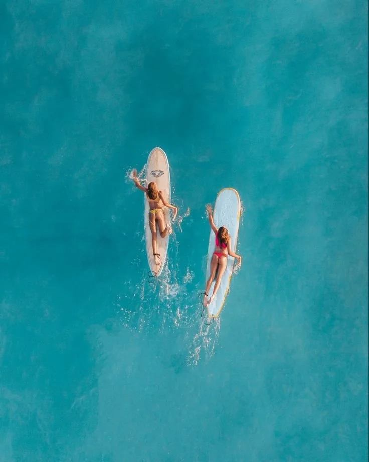 Twee vrouwen surfen op zee, gezien van bovenaf – lifestylebeeld ESENSI