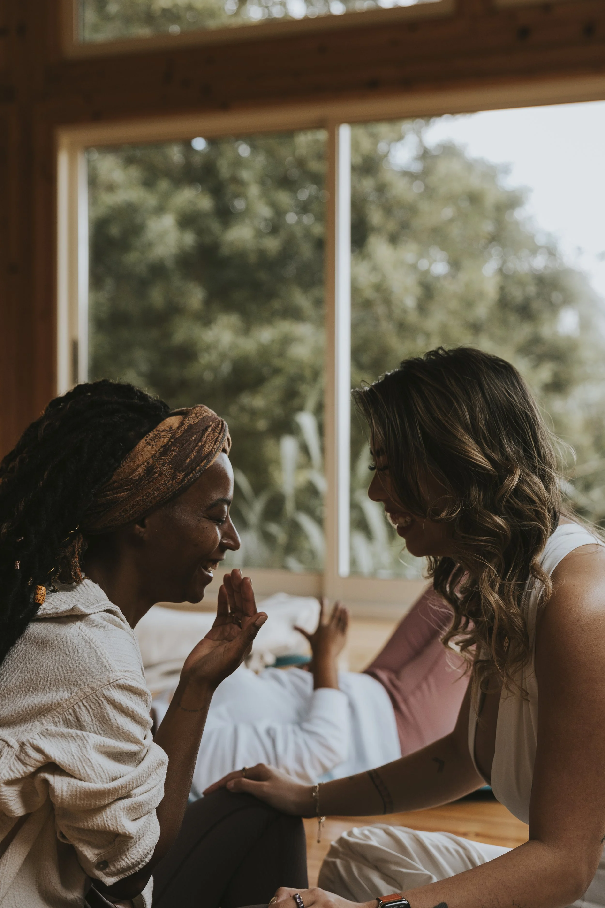 Twee vrouwen delen een warm mentoring-moment in een zonnig interieur – sfeerbeeld bij The Pearl Method van Lover Girl