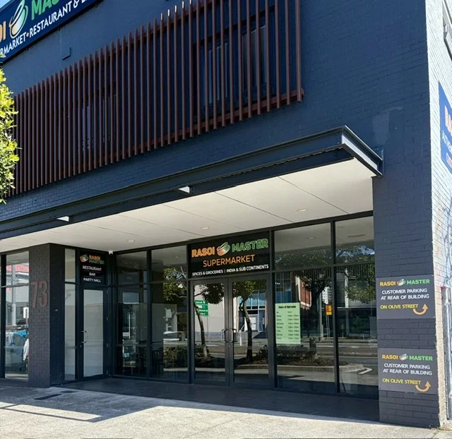 View of large glass windows and doors at the entry to an Indian restaurant with signage for 'Rasoi Master Cafe' in Southport.