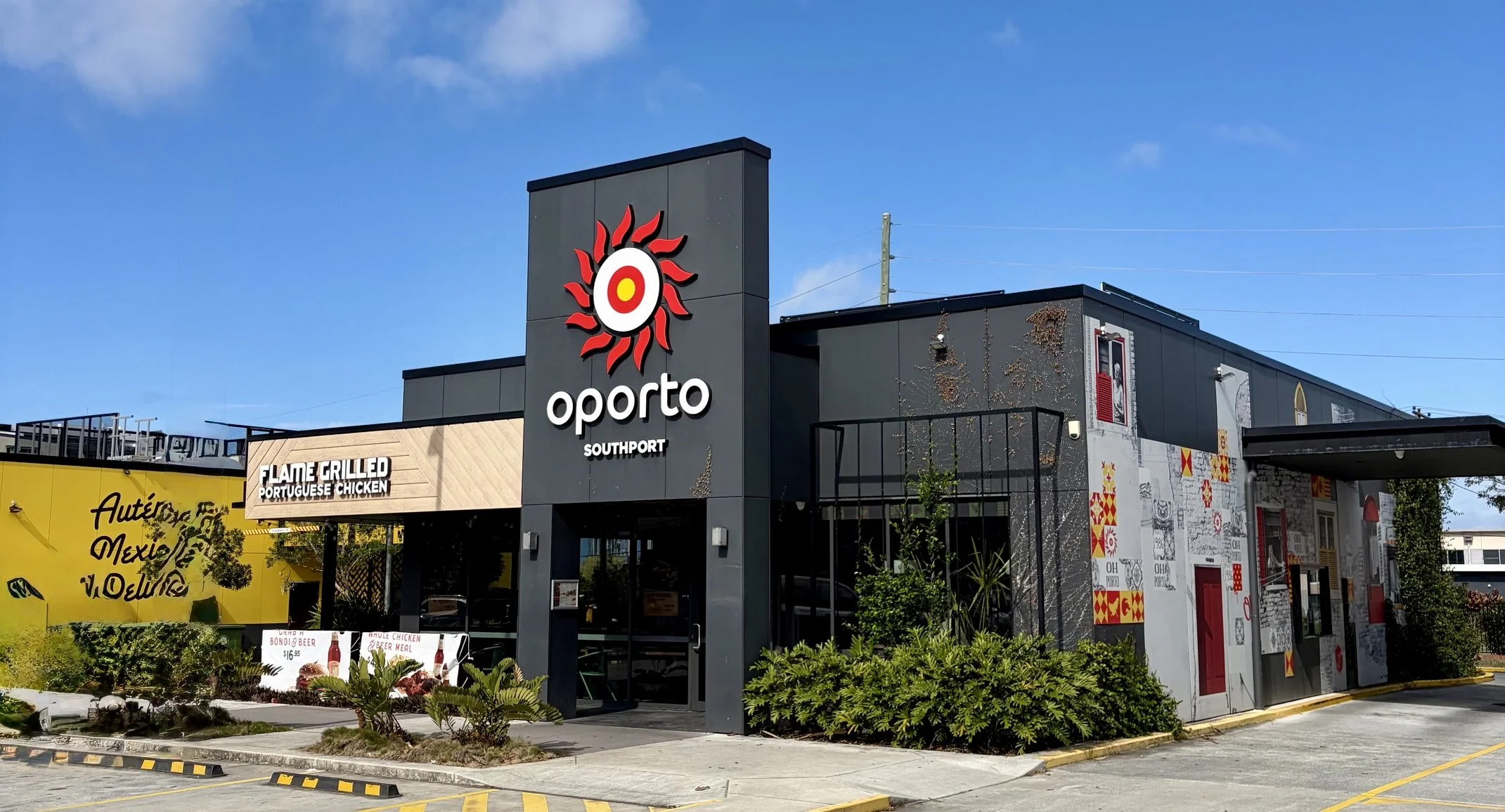 View of the outside of 'OPORTO' Southport showing the drive through on the right hand side and parking out the front of the new build with large neon logo on the high portico on a sunny day.
