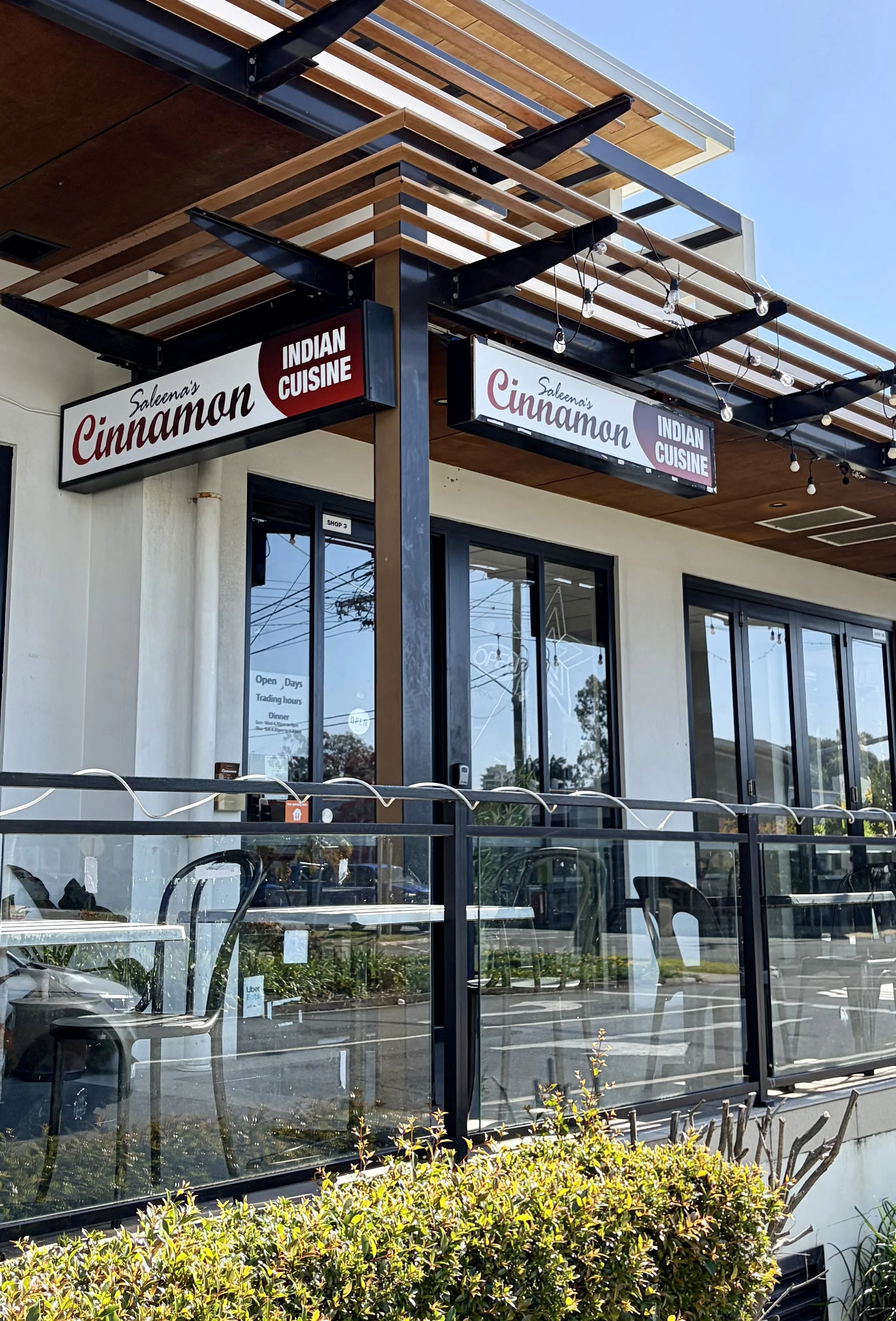 Modern Indian restaurant elevated from street level with tables out the front.with tables out the front and