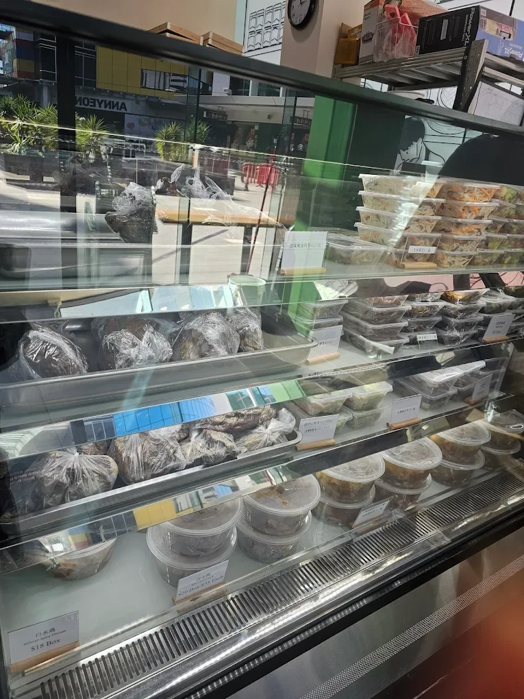 Display case with packaged food items, including wrapped buns or pastries on the left and prepackaged salads or dishes on the right in a food store.