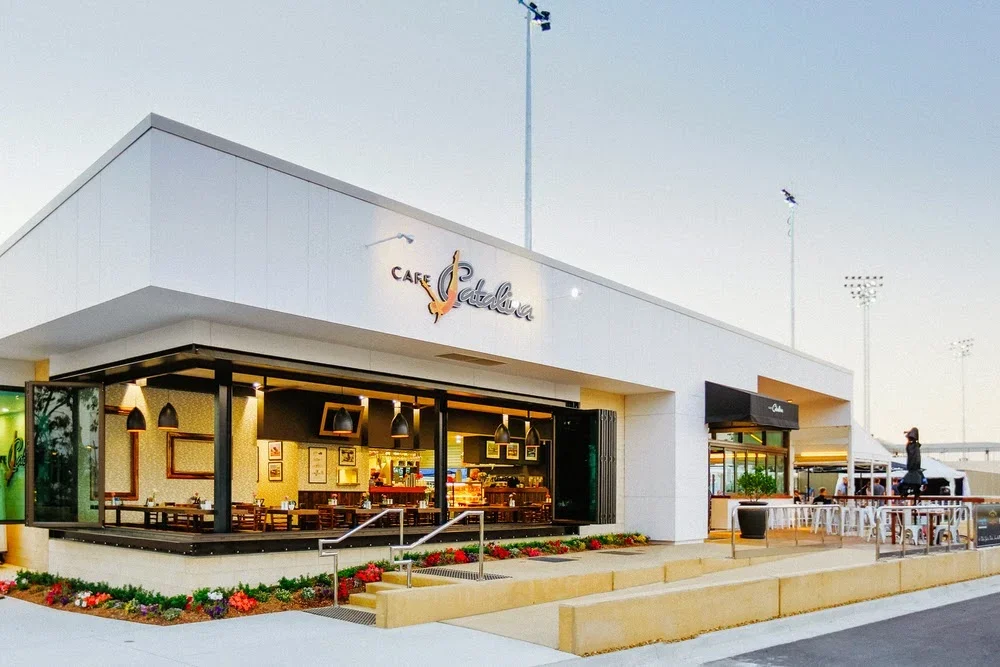 Exterior of Café Catalina with outdoor seating, window views of interior, and a woman walking nearby.