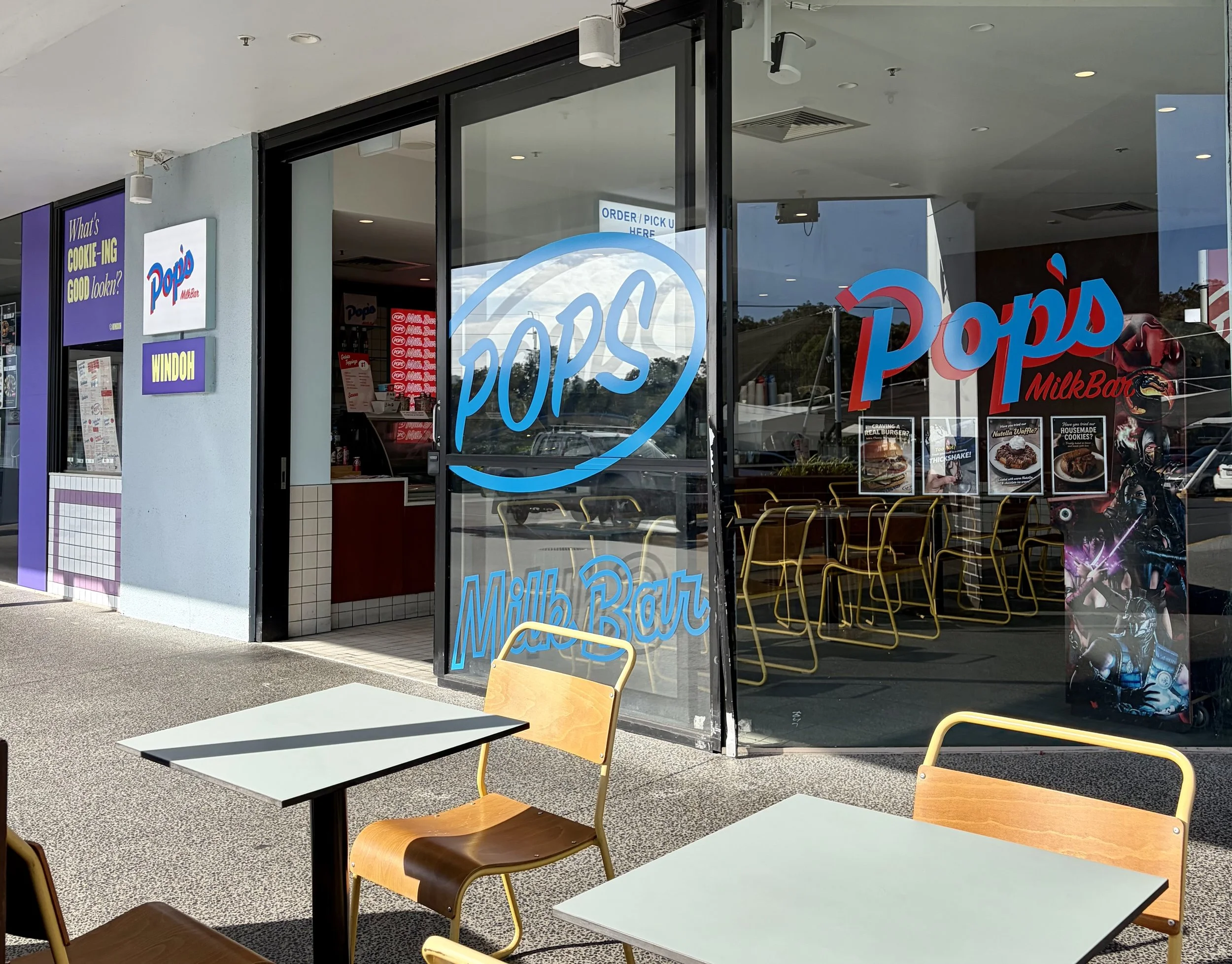 Outside view of colourful milkbar with tables and chairs out the front.