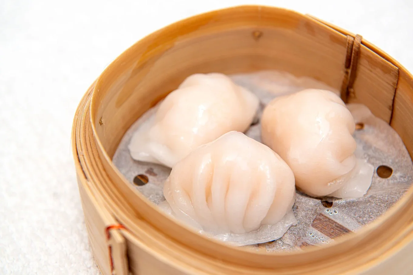 Steamed dumplings in a bamboo steamer basket.
