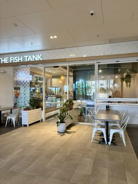 Exterior view of 'The Fish Tank' seafood restaurant in Southport showing tables and chairs out front with planter boxes and foliage and the fish tank signage above.