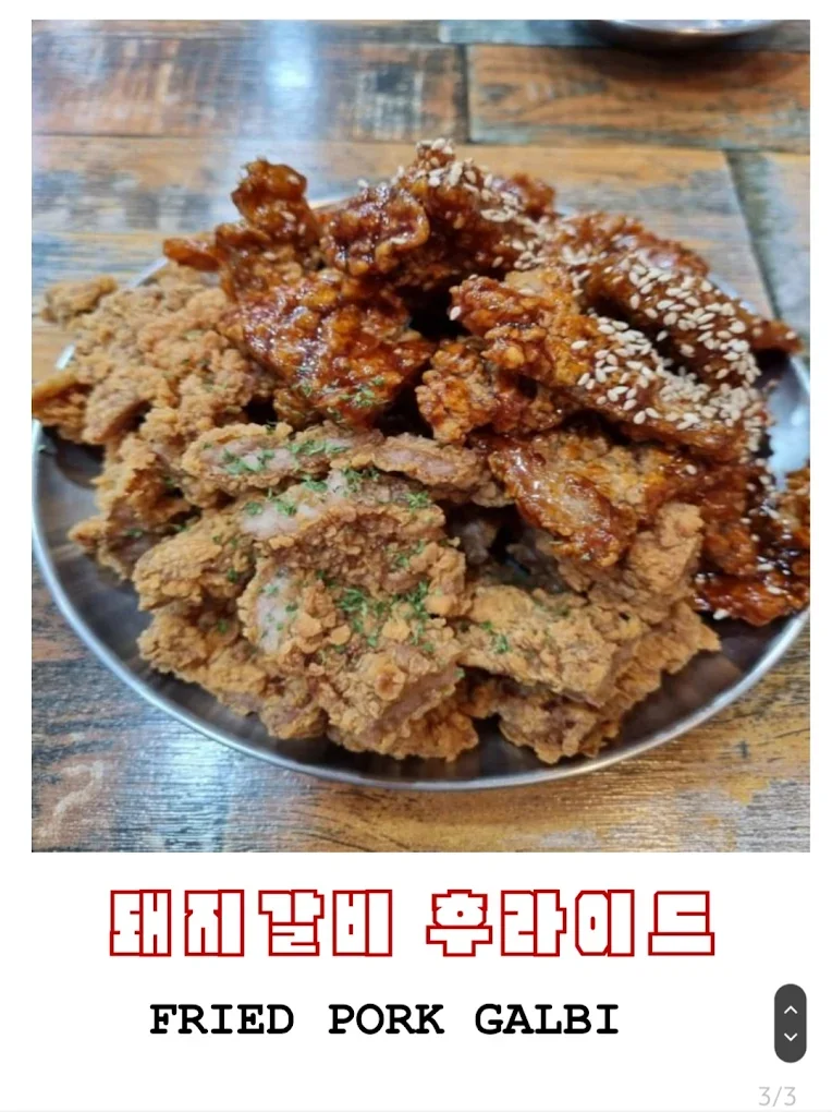 A plate of fried pork galbi with two types of fried pork, garnished with green herbs, served on a wooden table.