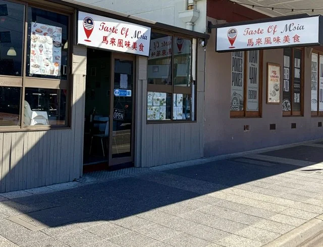 Street view of Malaysian restaurant "Taste of Msia" showing signage and a welcoming open door.