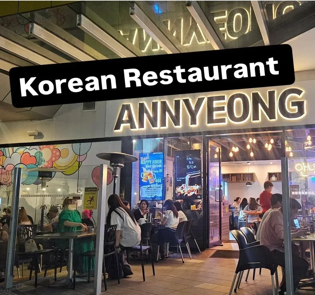 Exterior view of a Korean restaurant named ANNYEONG with people dining inside and outside.