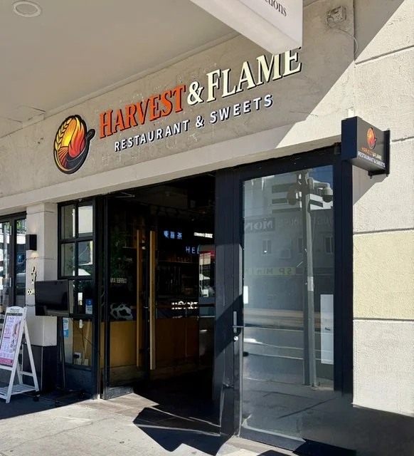 Signage of Harvest & Flame Restaurant & Sweets in Southport, modern looking building with Orange and white large backlit letters in orange and white.