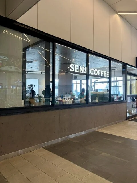 Modern glass frontage of SENS FUSION in Queens Street Village Southport with large illuminated SENS and COFFEE signage