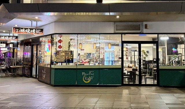 Night time view of the outside of "Flame King" Chinese restaurant and take away with bright Chinese motifs and Flame King logo.
